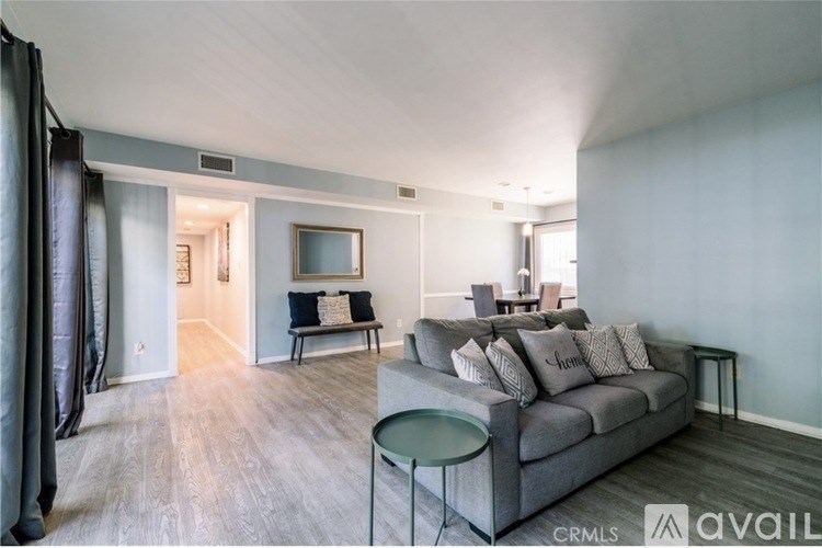A living room with a grey couch and a glass table.