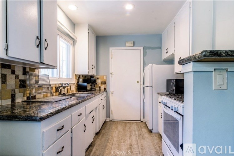 A kitchen with white cabinets and a black countertop.