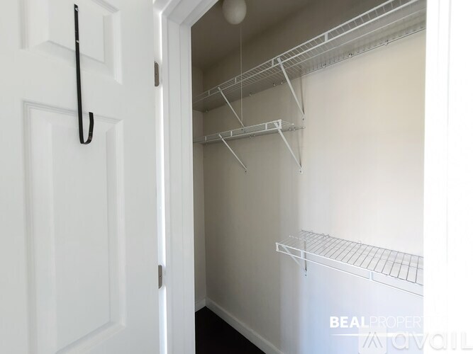 A white door is open to a small, empty closet with a metal rack.