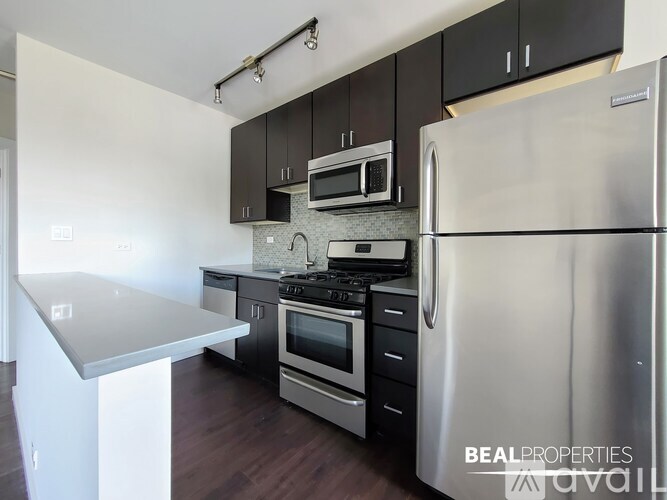 A kitchen with a refrigerator, stove, and microwave.