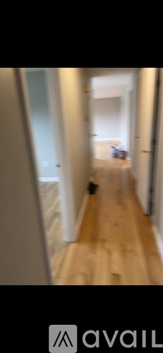 A hallway with a person sitting on a couch.