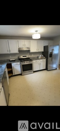 A kitchen with white cabinets and a refrigerator.