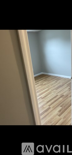 A room with wooden flooring and a wall.