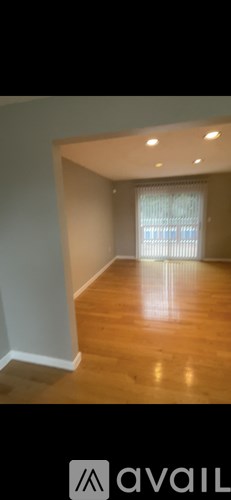 A room with wooden flooring and a window with blinds.