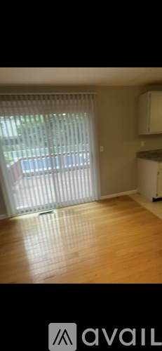 A room with wooden flooring and a window with blinds.