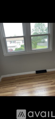 A room with a window and wooden flooring.