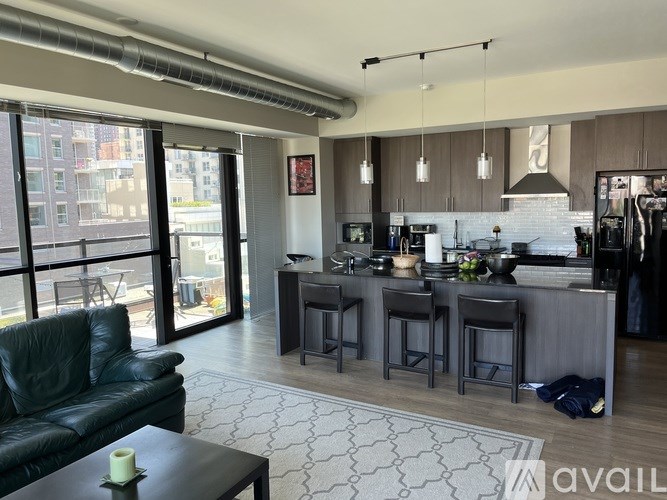 A modern kitchen and living room with a black leather couch and a coffee table.