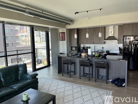 A modern kitchen and living room with a black leather couch and a coffee table.