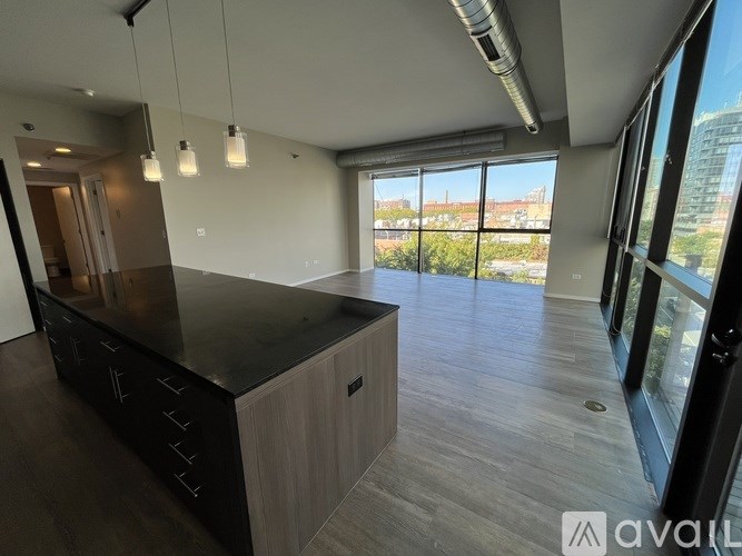 A modern living room with black leather furniture and a large window overlooking a cityscape.