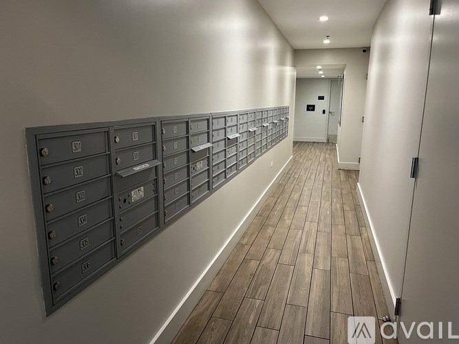 A long hallway with mailboxes on the wall and a door at the end.