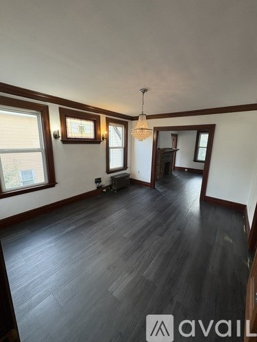 A room with wooden floors and a chandelier hanging from the ceiling.