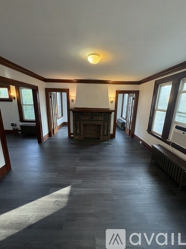 A large, empty room with wooden floors and a fireplace.