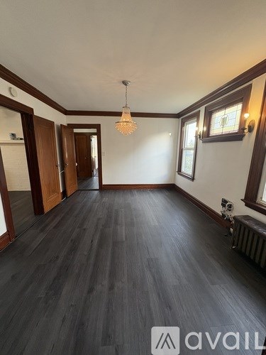 A room with wooden floors and a chandelier hanging from the ceiling.