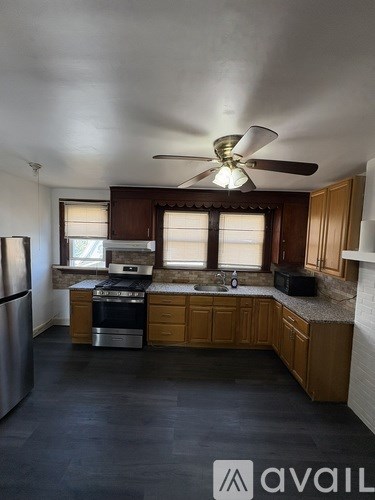 A kitchen with wooden cabinets and a black floor.