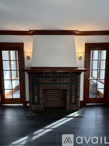 A fireplace with a tile surround in a room with wooden floors and doors.