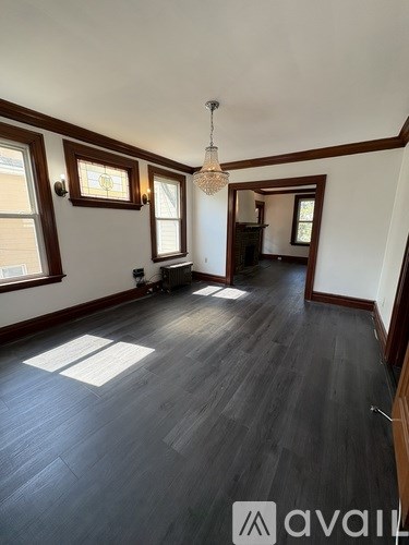 A room with wooden floors and a chandelier hanging from the ceiling.