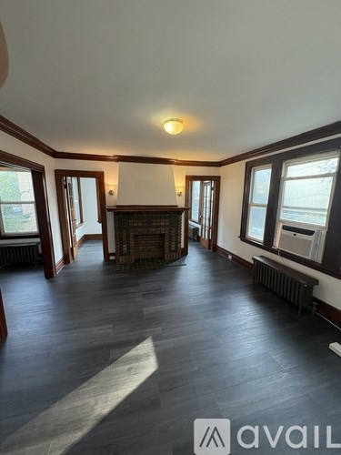 A spacious room with wooden floors and a fireplace.