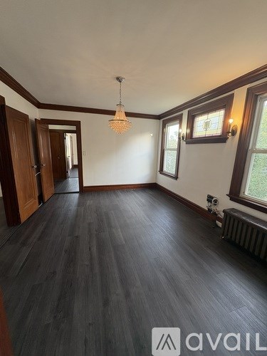 A room with wooden floors and a window with a view of greenery outside.