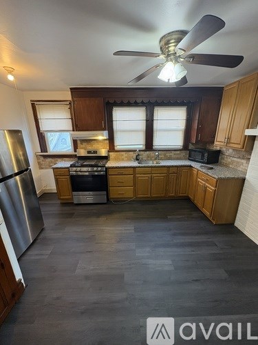 A kitchen with wooden cabinets and a stainless steel refrigerator.