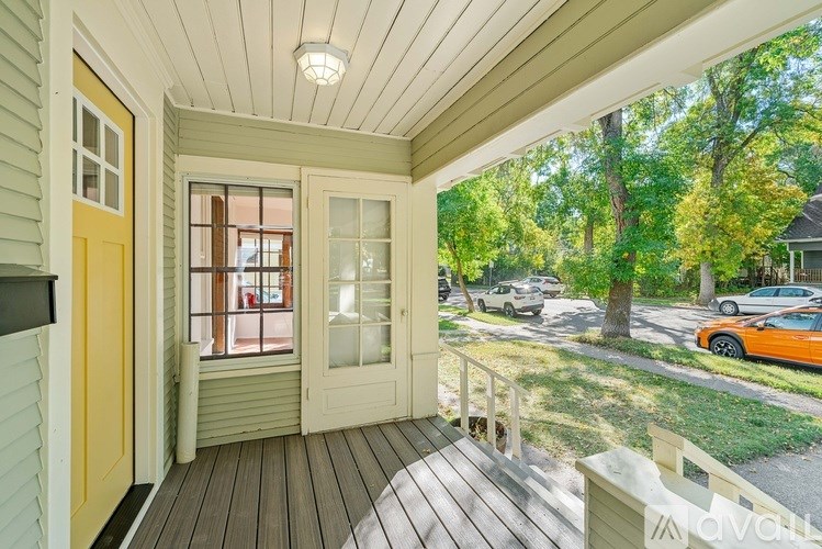 A wooden deck with a yellow door and a glass window overlooking a street.