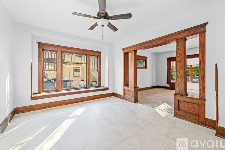 A room with a ceiling fan and a large window.