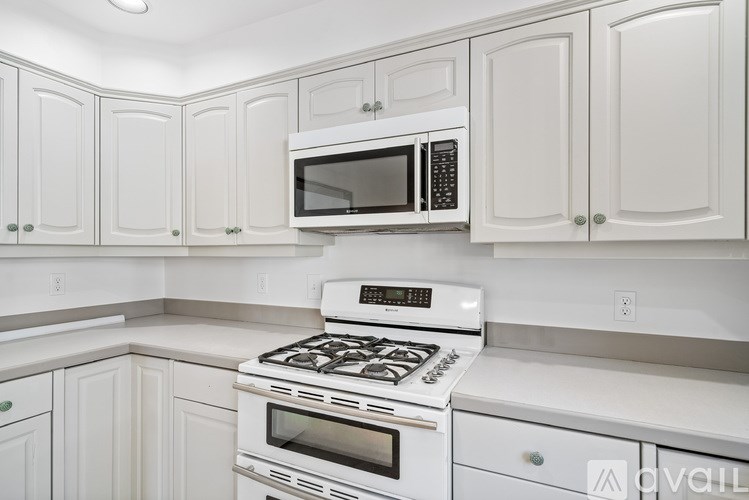 A white kitchen with a stove, oven, microwave, and cabinets.