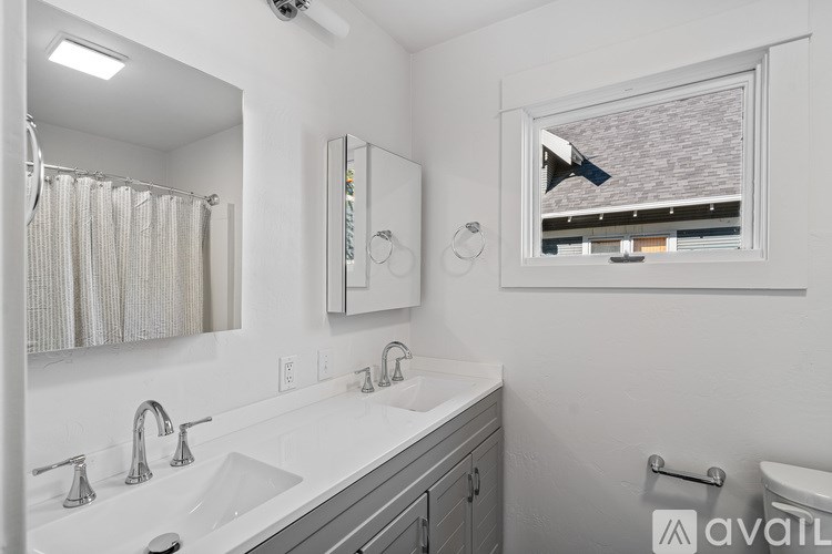 A bathroom with a large mirror, a sink with two faucets, and a towel rack.