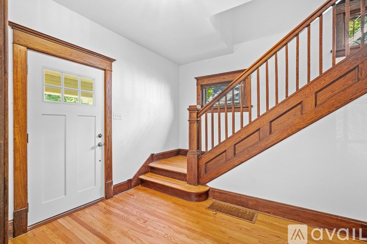 A wooden staircase with a white door and a window.