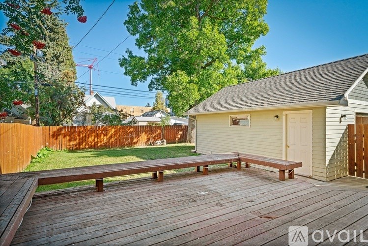 A wooden deck with a bench in front of a house.