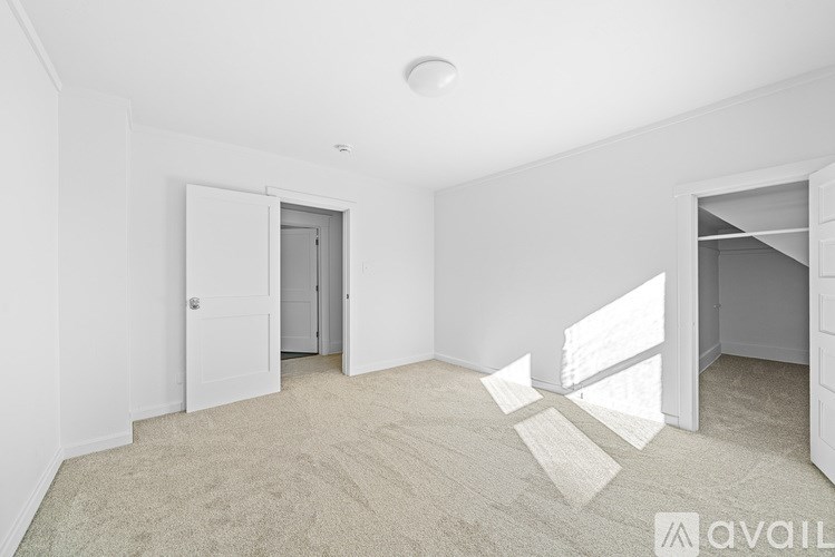 A room with a carpeted floor and two open doors.