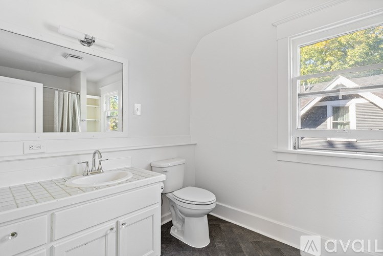 A white bathroom with a toilet, sink, and mirror.