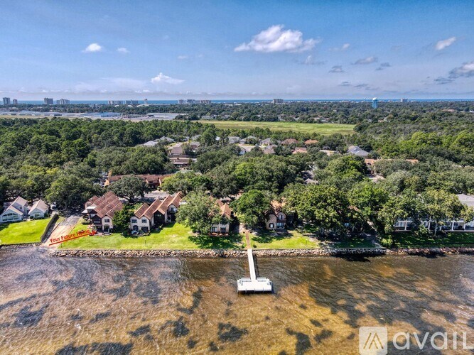 A bird's eye view of a residential area with houses, trees, and a body of water.