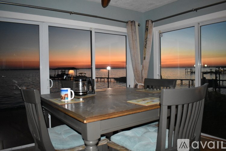 A table with a cup and a pot on it with a view of the sea.