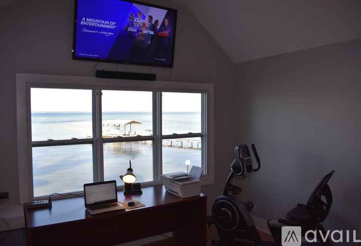 A room with a laptop, a lamp, a book, and a TV showing a movie.