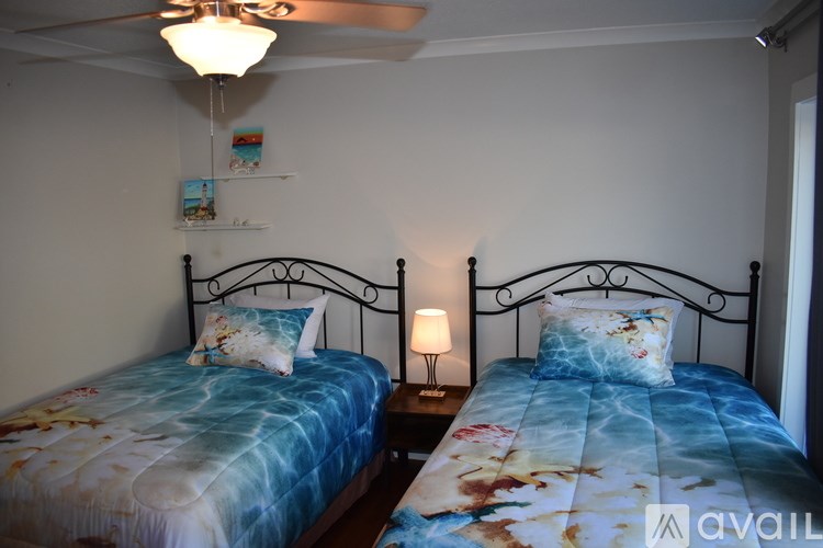 Two twin beds with floral bedspreads in a room with a ceiling fan.