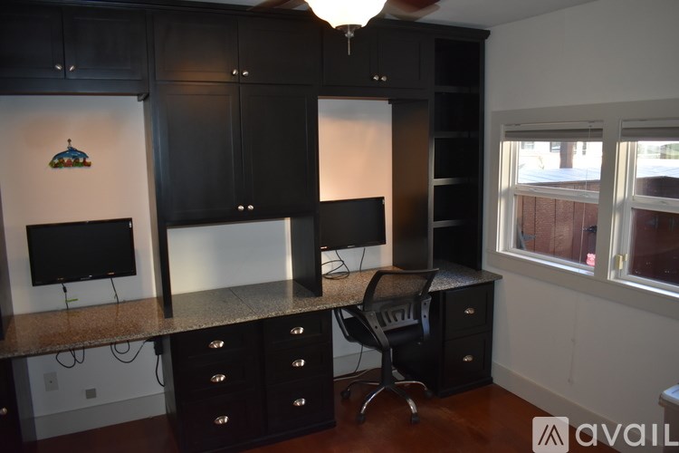 A black and white kitchen with a TV and a fan.