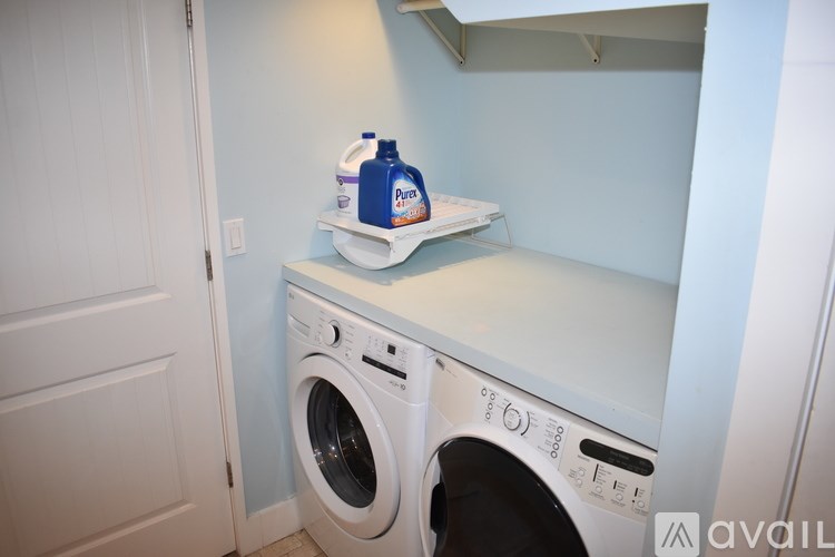 A white washing machine with a blue bottle of detergent on top.