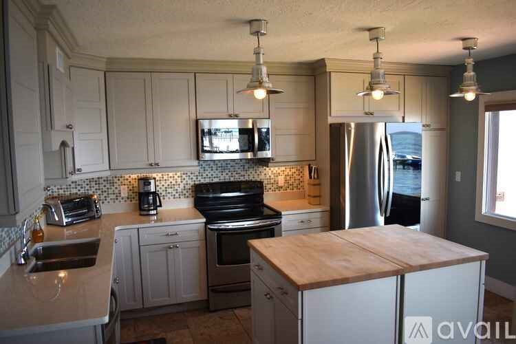A kitchen with white cabinets and a wooden island.