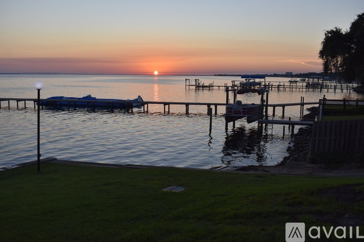 A sunset view of a dock with boats and a lamp post.