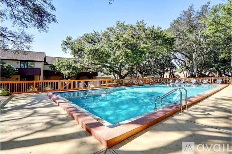 A large outdoor swimming pool surrounded by trees and a building.
