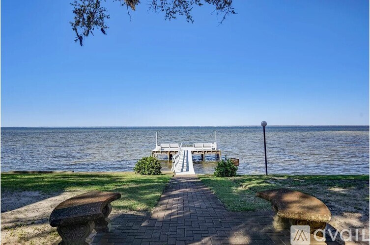 A bench is on a paved area next to a body of water.