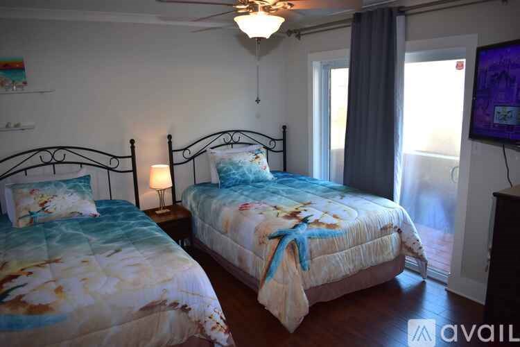 Two twin beds with floral bedspreads in a room with a ceiling fan.