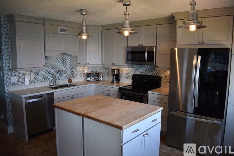 A kitchen with a wooden counter top and stainless steel appliances.