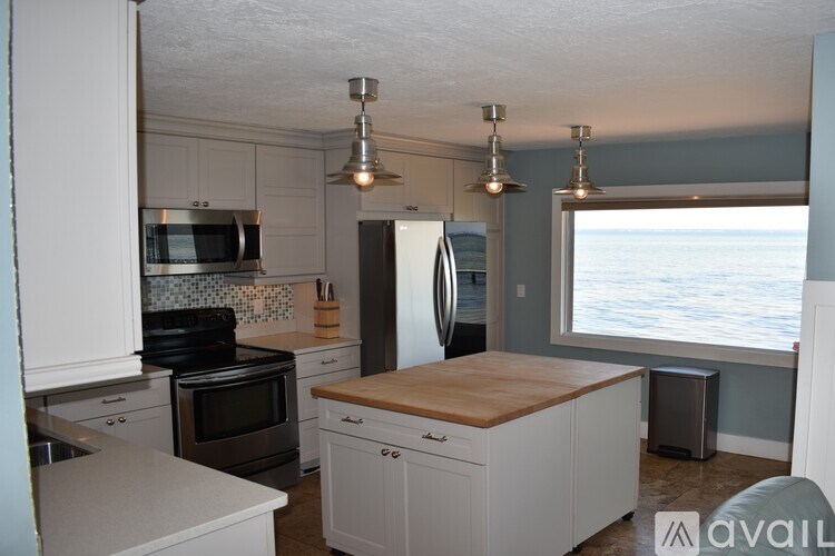 A kitchen with white cabinets and a wooden island.