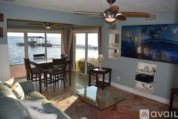 A living room with a glass table and a view of a docked boat.