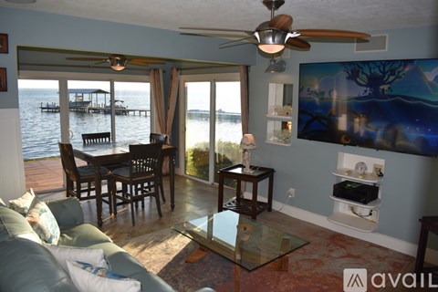 A living room with a glass table and a view of a docked boat.