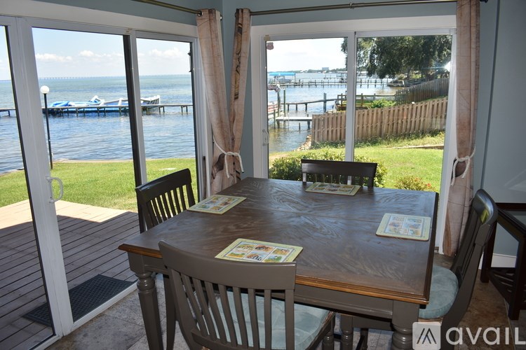 A table with chairs and a view of the water is set up on a deck.
