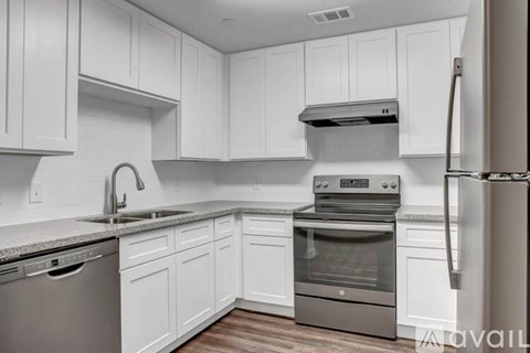 A modern kitchen with white cabinets and stainless steel appliances.