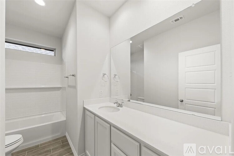 A white bathroom with a toilet, sink, and mirror.