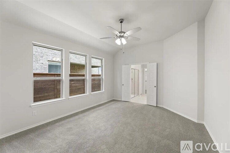 A spacious room with a ceiling fan and three windows.